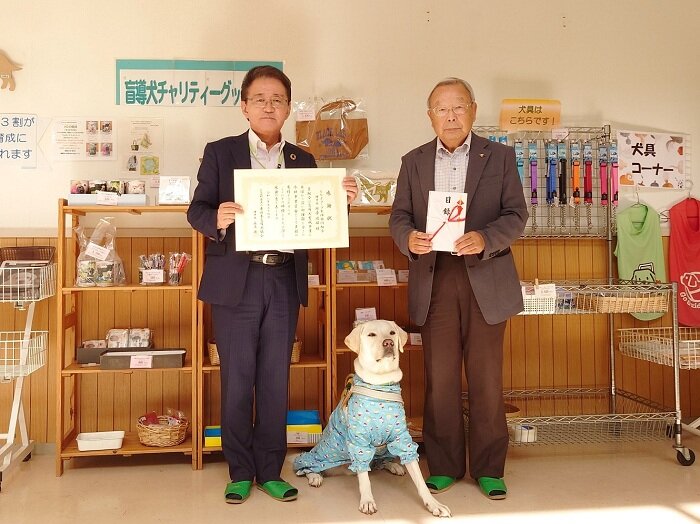 (左側)とちぎコープ理事長 塚原政雄　(右側)東日本盲導犬協会理事長 眞尾 博様 PR犬のIZUMO(イズモ)君 ３歳オス